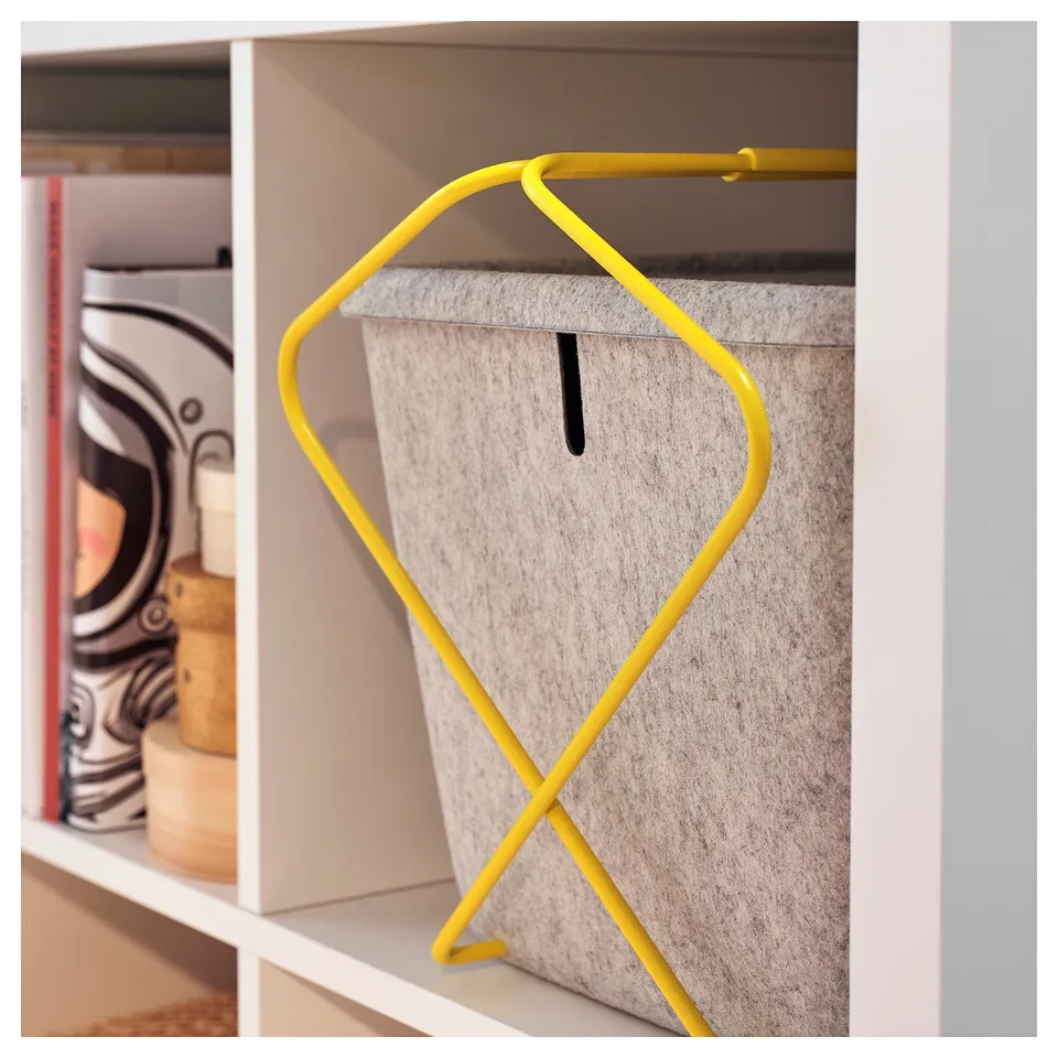 A bright yellow handle on a grey felt storage basket on a white shelf.