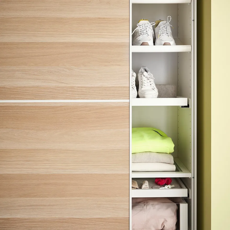 KOMPLEMENT wooden closet with white shelves; pink, white, grey trainers; light green clothes.
