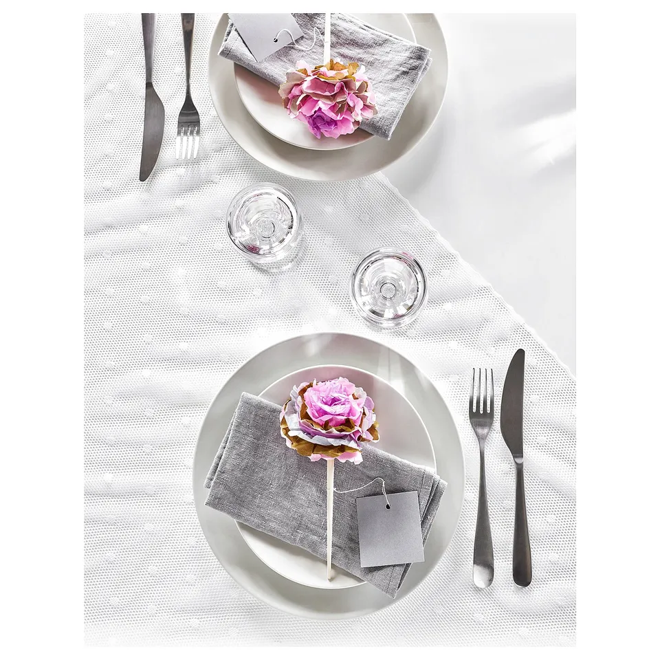 Elegant table setting with BEHAGFULL stainless steel cutlery, white plates, floral napkins, and clear glasses.