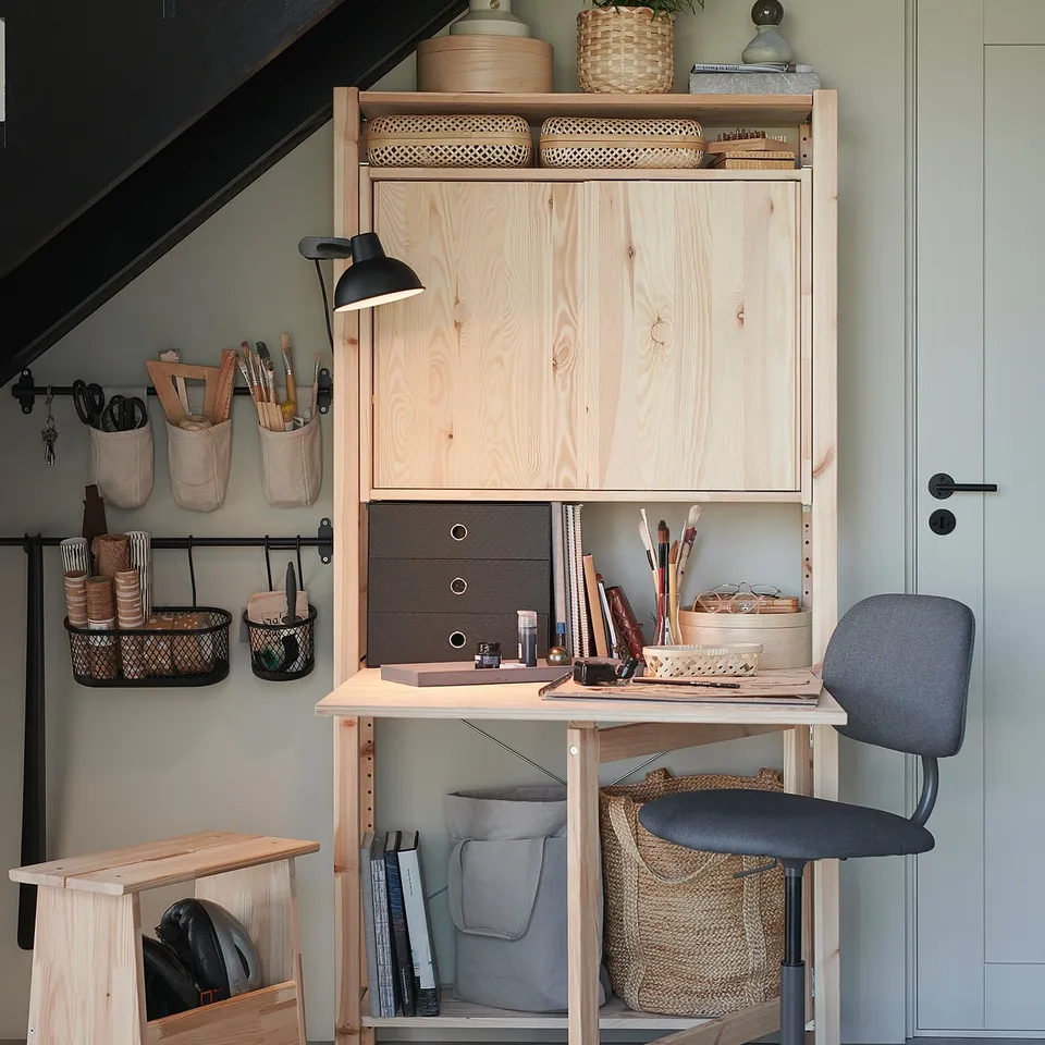 Home office setup with IVAR pine furniture. Wooden desk, chair, and storage unit. Art supplies and books organised neatly.