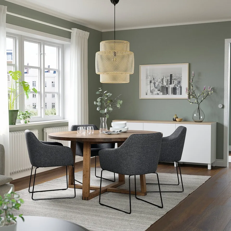 Green dining set with wooden table, grey chairs, and overhead light fixture.
