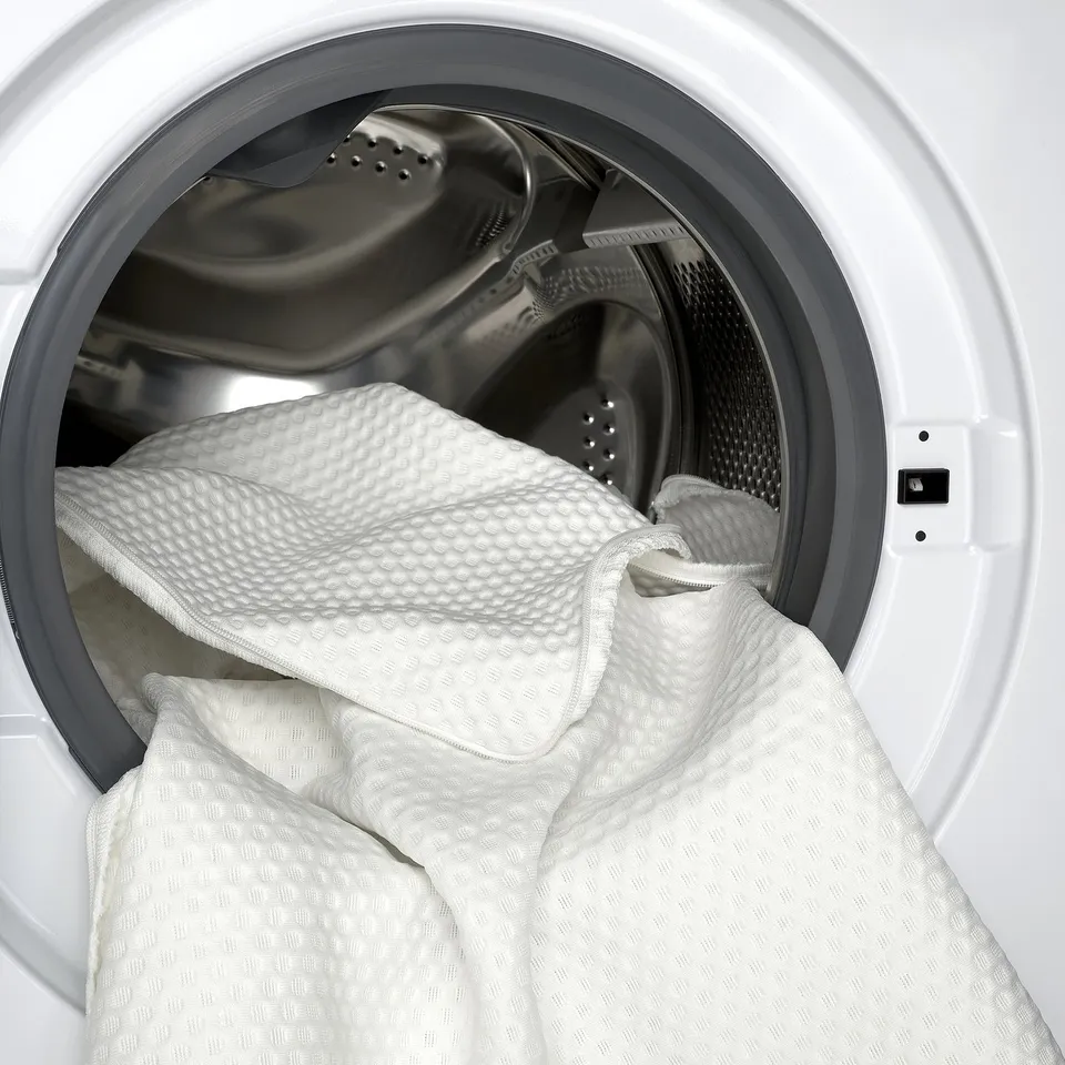 White textured blanket filling a tumble dryer. The fabric design ensures comfort and durability.
