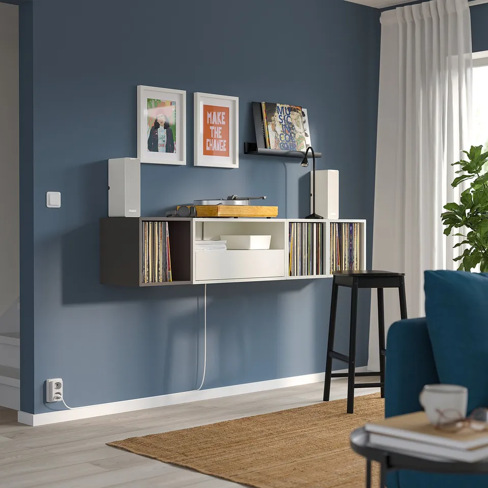Blue wall shelf with records, art, and window. Minimalist decor.