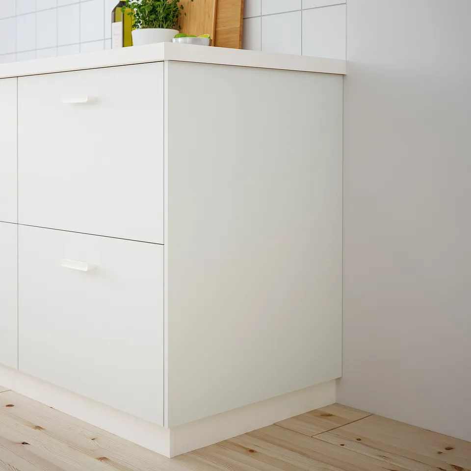 White VALLSTENA kitchen cabinet with smooth surface against tiled wall, corner-fitting with drawers and countertop.