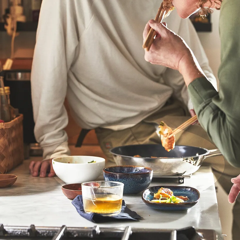 Two people cooking in a kitchen using wooden utensils and bowls with an IKEA 365+ pan.