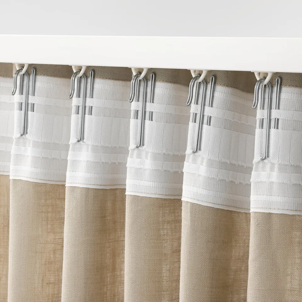 Beige curtain section with multiple clear hooks gripping white gathering tape, showcasing easy hanging functionality.