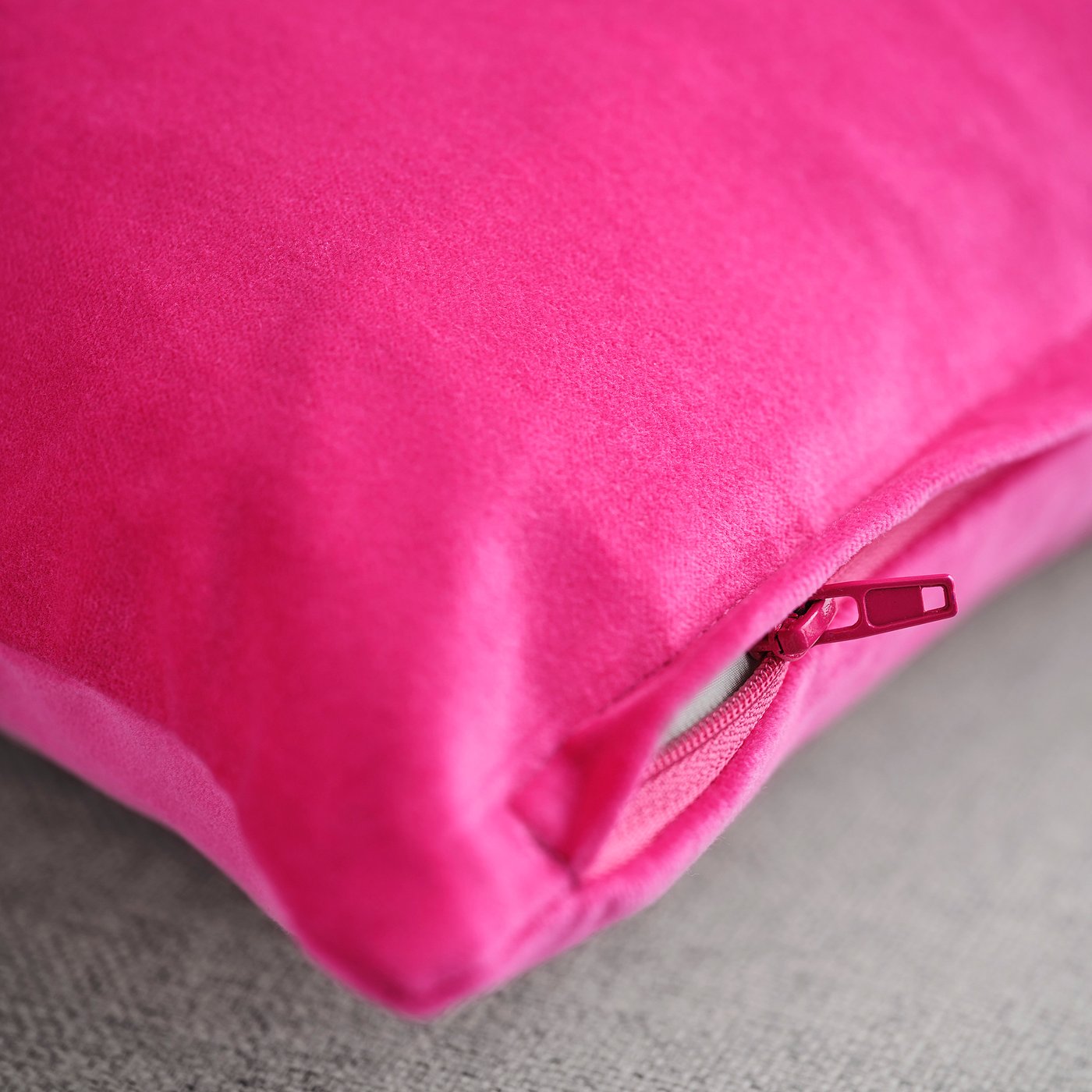 Bright pink cushion cover made of soft, textured cotton velvet with a visible zip.