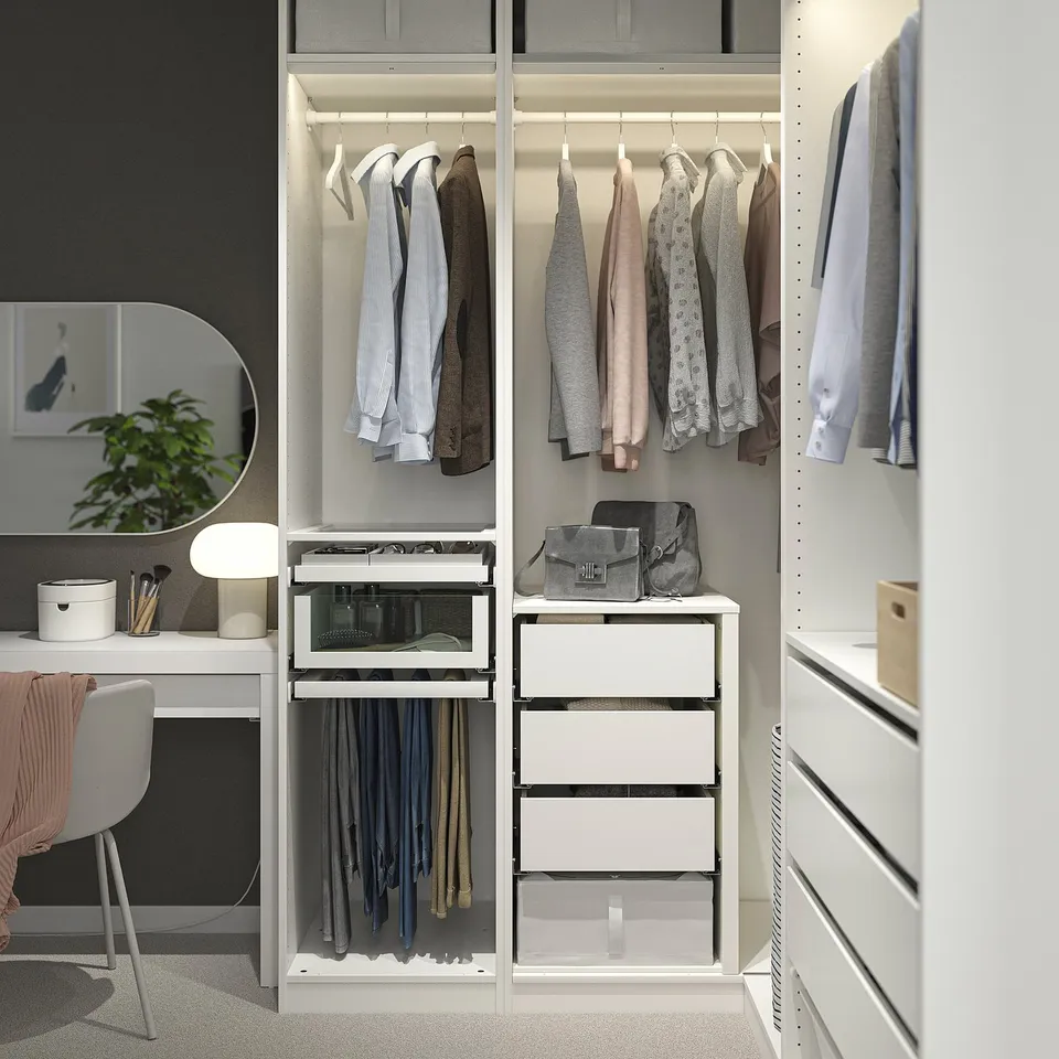 White corner wardrobe with multiple compartments for clothes, accessories, and a vanity with chair.