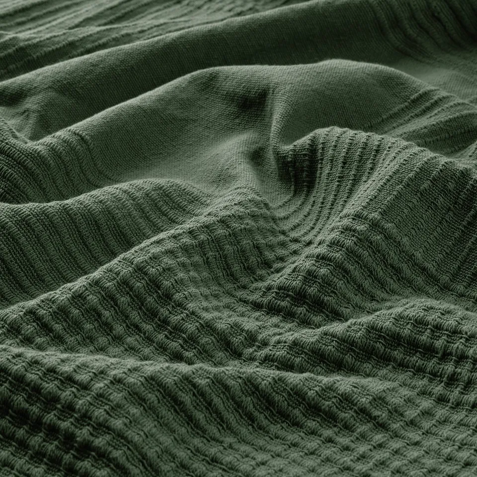 Soft, textured green cotton blanket, showcasing quality weave and comfort.