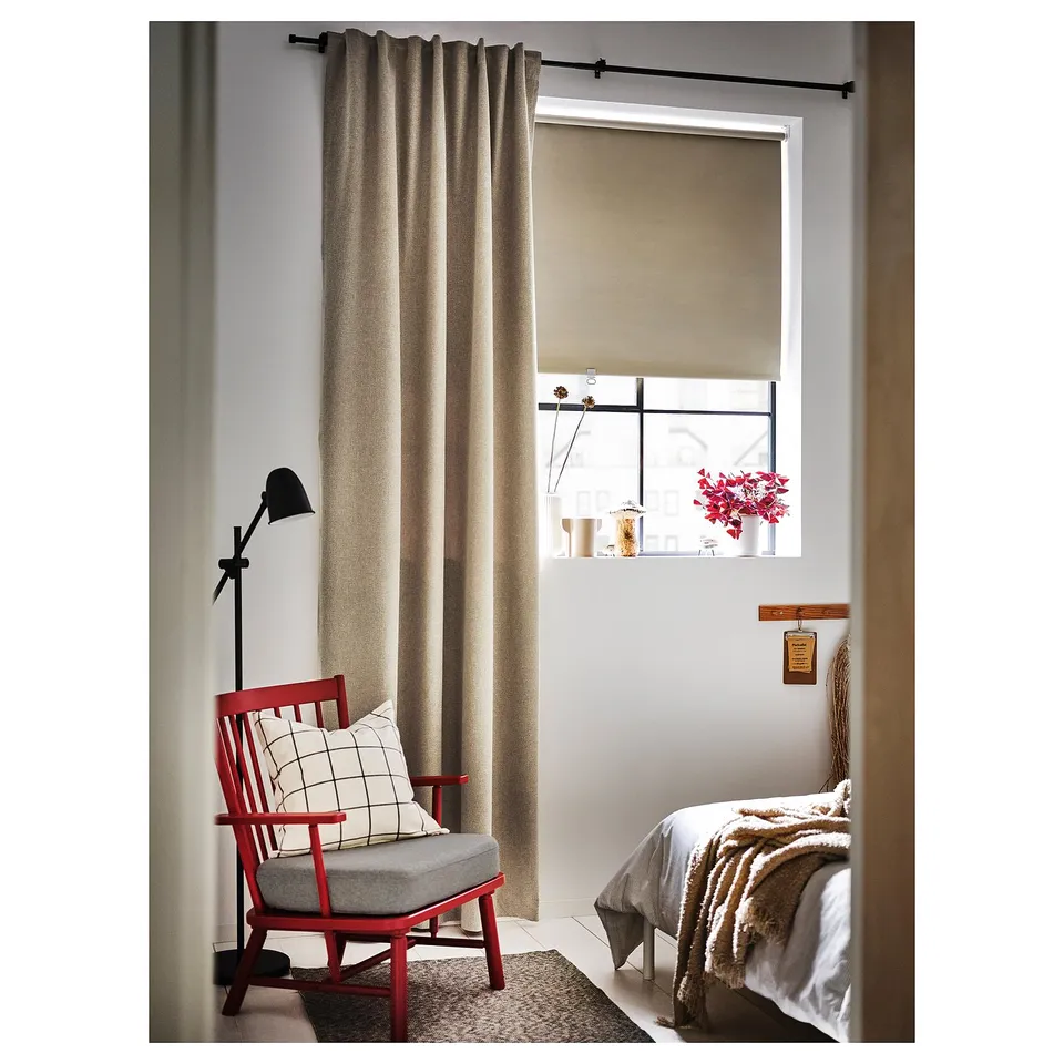 Cosy corner with red chair, grey cushion, and window with beige curtains and shelf of vases and flowers.