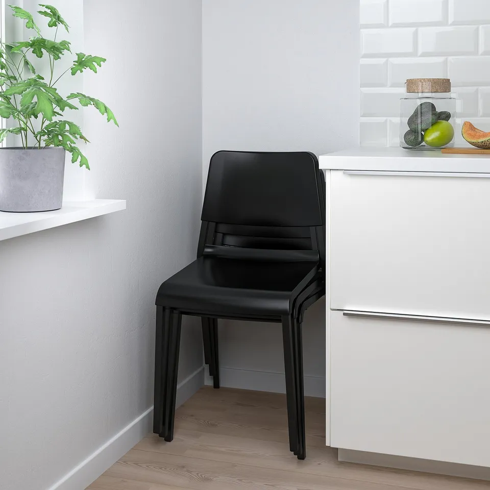 Black chair next to white cabinet with fruits on top.