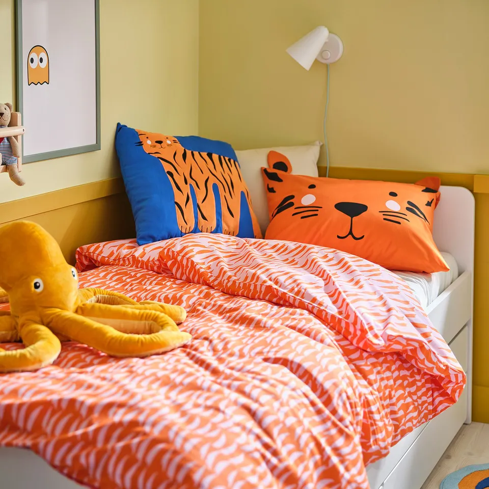 Vibrant orange tiger-themed kids bedding, featuring playful pillows and a cosy blanket, fitting perfectly on a white bed.