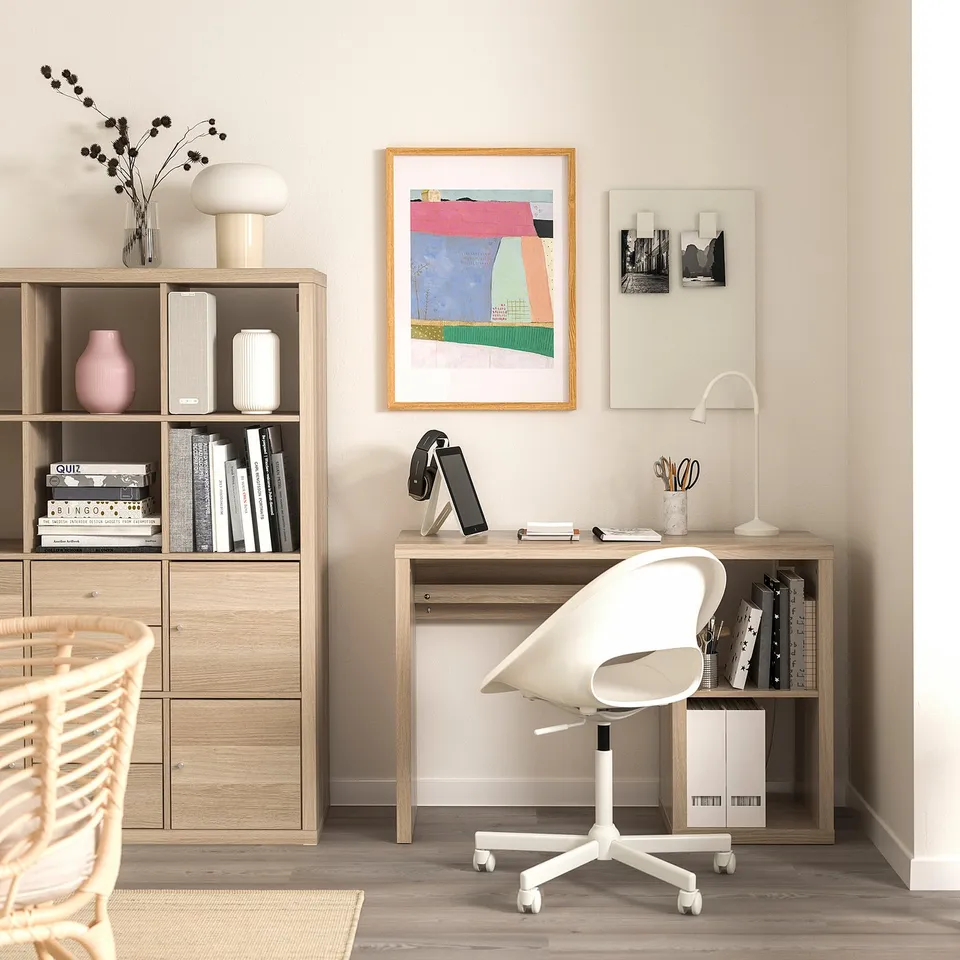 Modern home office setup with a honeycomb paper-filled KALLAX desk and bookshelves, white chair, and colourful artwork.