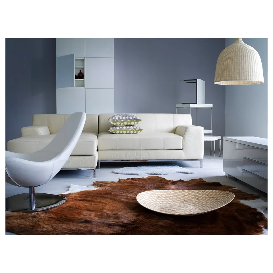 Modern living room: sectional, rug, pendant lamp, blue walls, side chair, cushions, bowl.