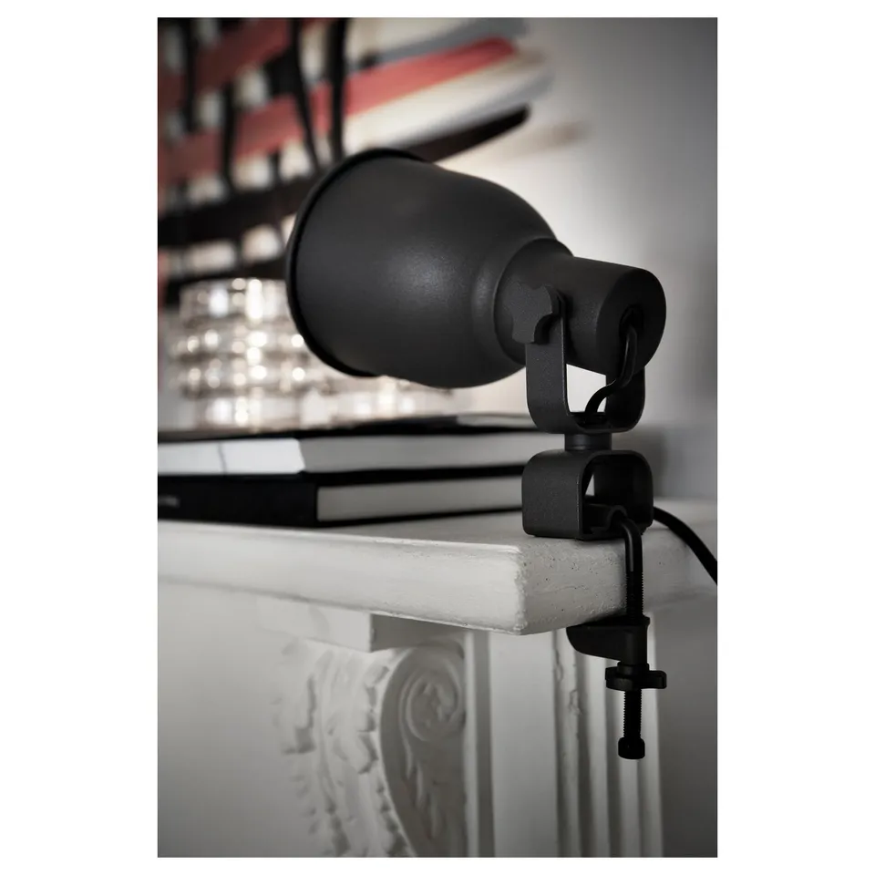 Black adjustable clamp spotlight on white surface, aiming upward.
