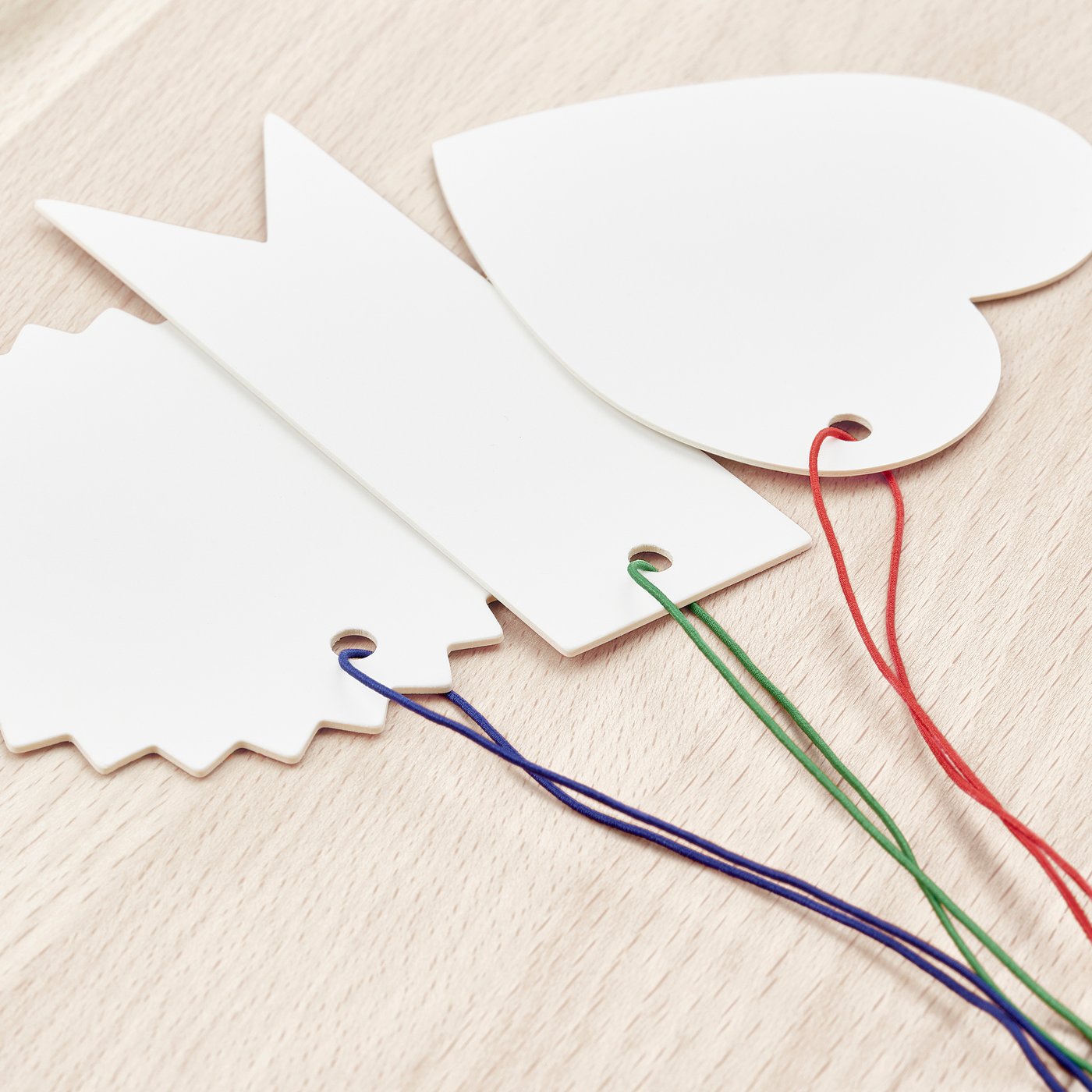 Three wooden tags: flag, heart, label, colourful strings.