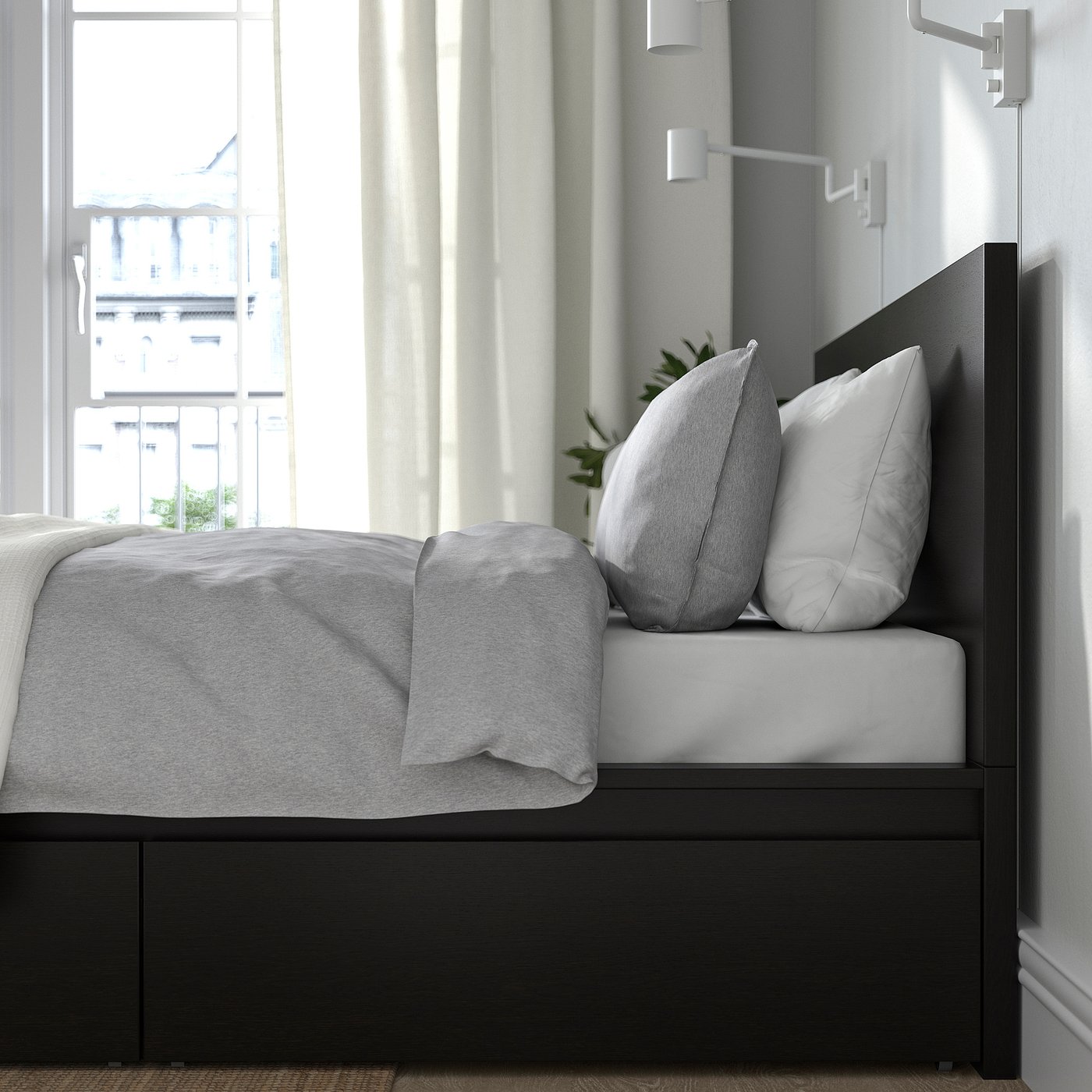 Bedroom scene: cosy bed with white pillows, grey blanket, against wall with windows. Lighting on bed frame.