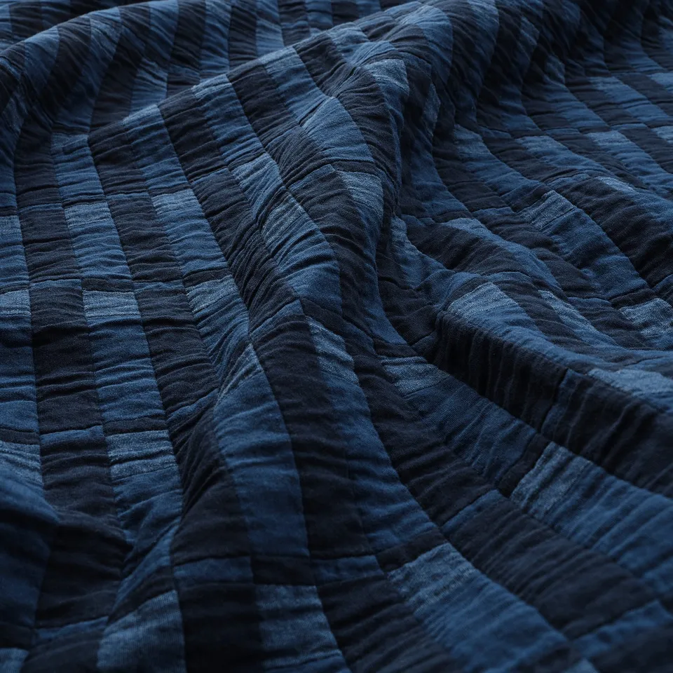 Close-up of folded dark blue chequered blanket, showcasing texture and stitching.