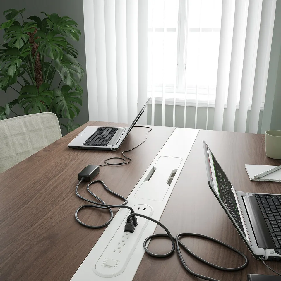 Conference table with laptops, power strips, and plant. Perfect for meetings and work with built-in cable management.