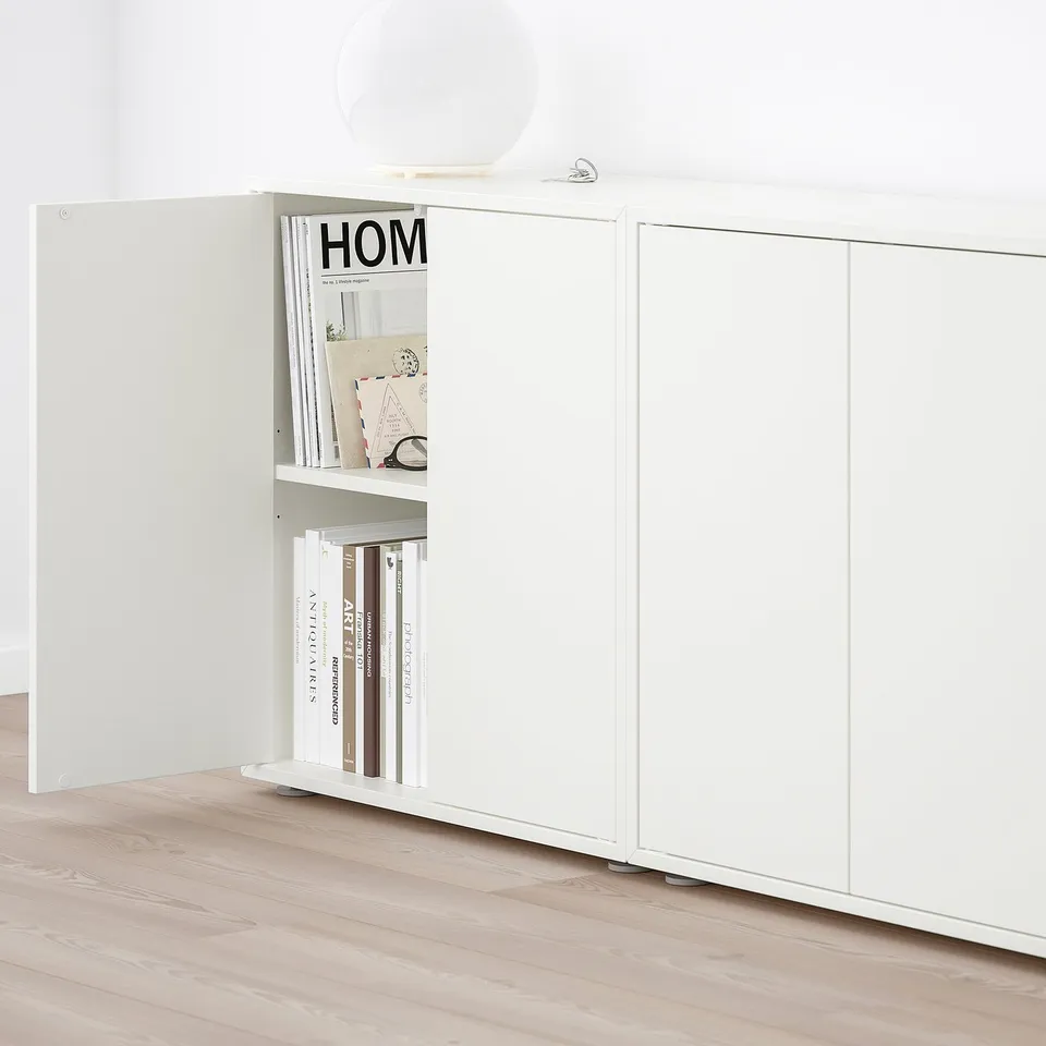 White EKET storage unit with open door revealing shelves holding books and decor.