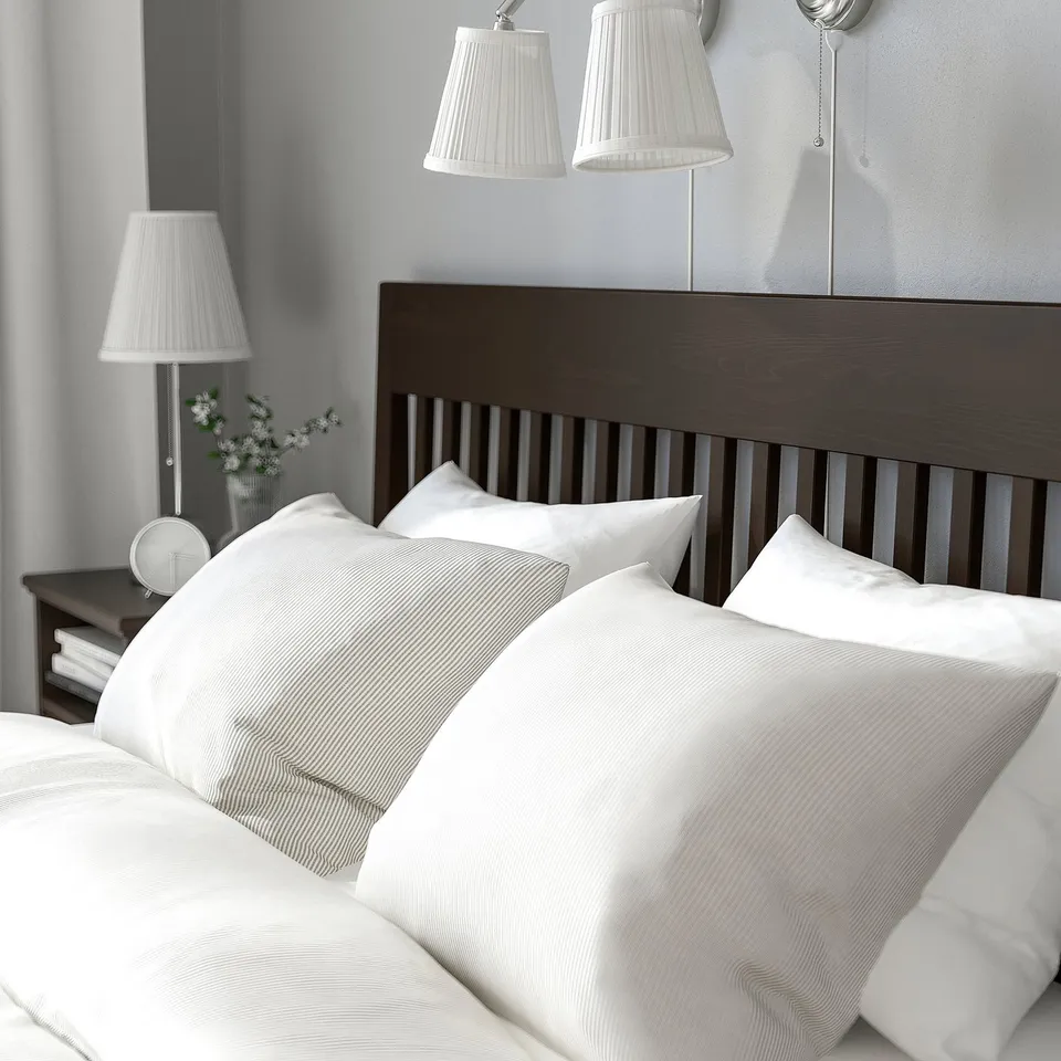 Cosy bedroom with white linens on a dark wooden bed frame, featuring built-in slatted base for mattress support and airflow.