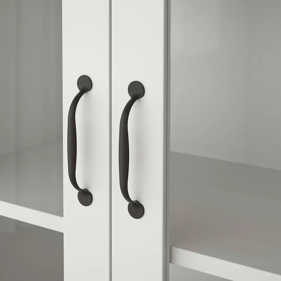 Close-up of two sleek, modern handles on a clean, white cabinet. Curved design, matte finish, attached firmly to smooth surface.