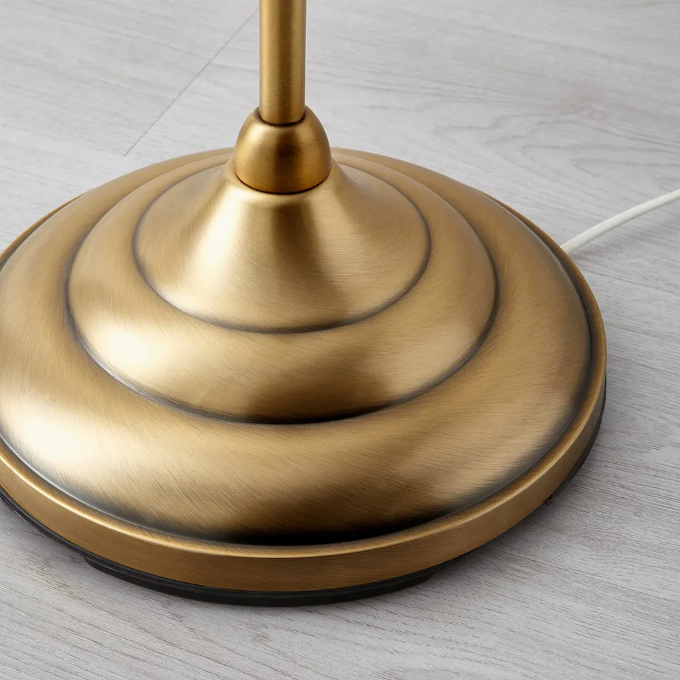 Gold table lamp base, sleek design on wooden surface. Intricate detailing, quality finish.