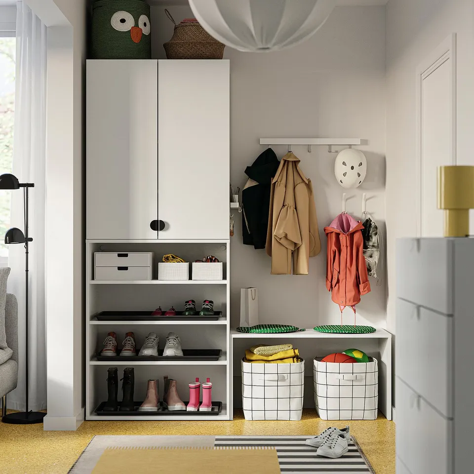 Organised entryway with white SLÅTTERVALL baskets in kallax unit. Coats hang above, shoes stored below, stylish and functional.