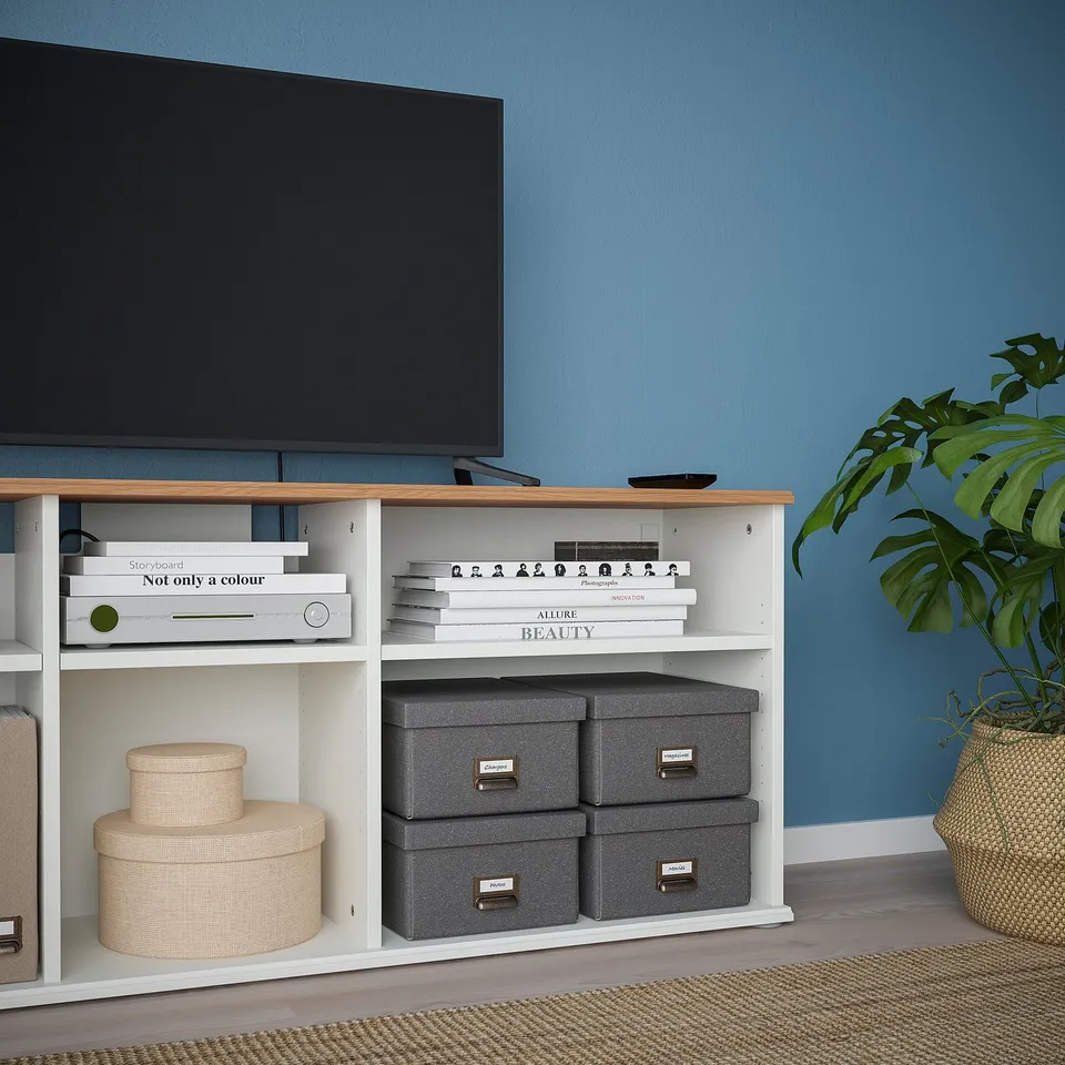 A modern tv stand with open shelves, holding books and storage boxes, featuring a minimalist design.