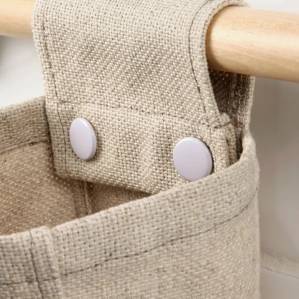 A close-up of a durable fabric hanging basket with wooden rod, featuring rustic natural texture.