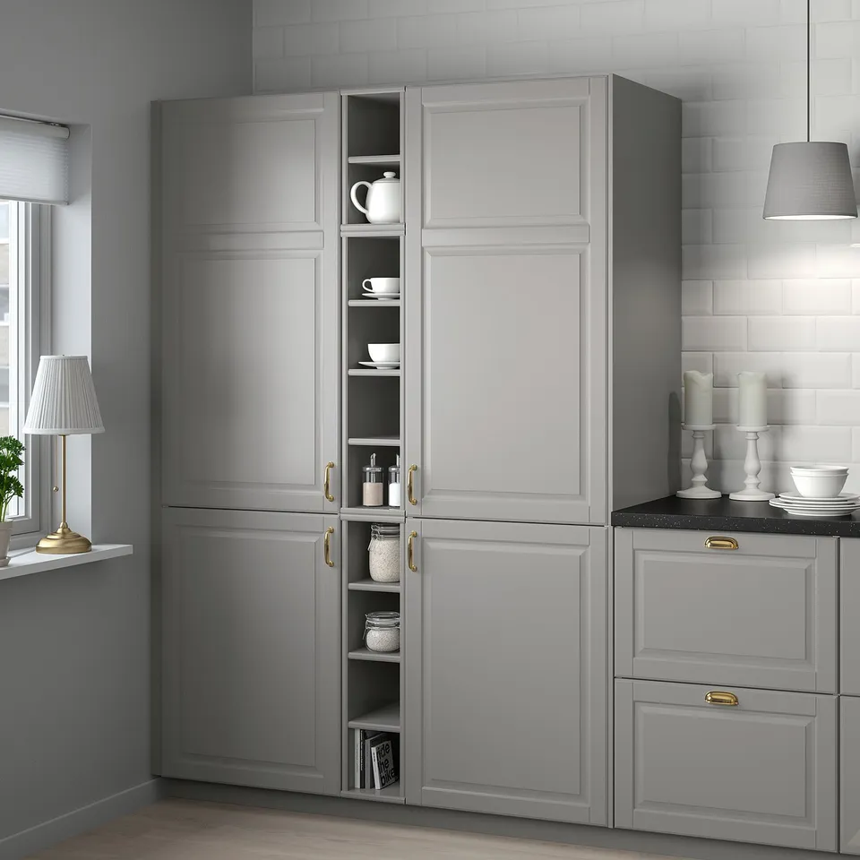 Modern grey TORNVIKEN cabinet with open shelves holds white dishes, teapot, and jars. Sits between other cabinets, showcasing items.