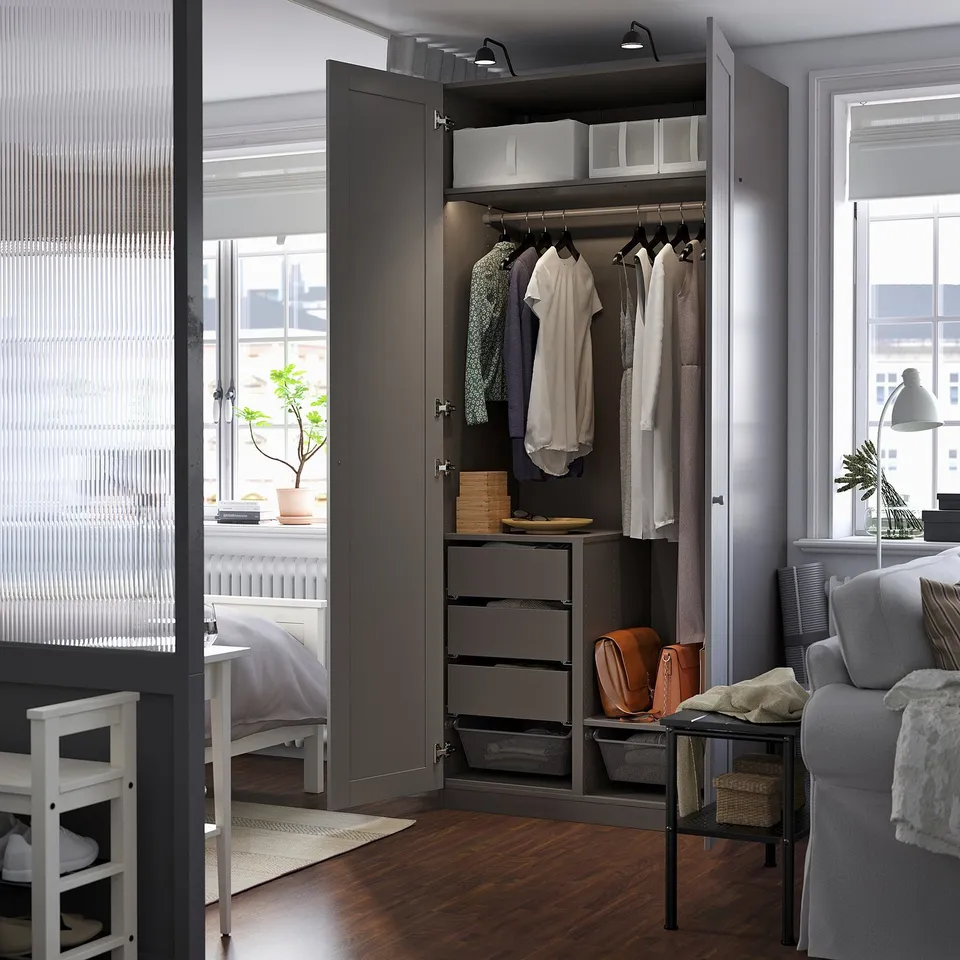 Modern PAX wardrobe with clothes, shelves, drawers, storage, and bright lighting in open space.