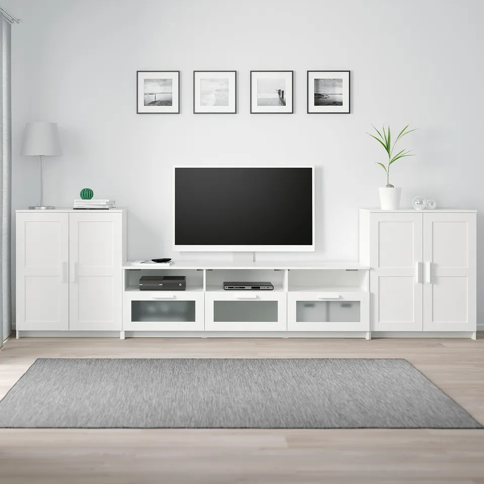 White tv bench with drawers & glass doors, flat-screen tv, and matching cabinets with decor. Photos above, grey rug on wood floor.