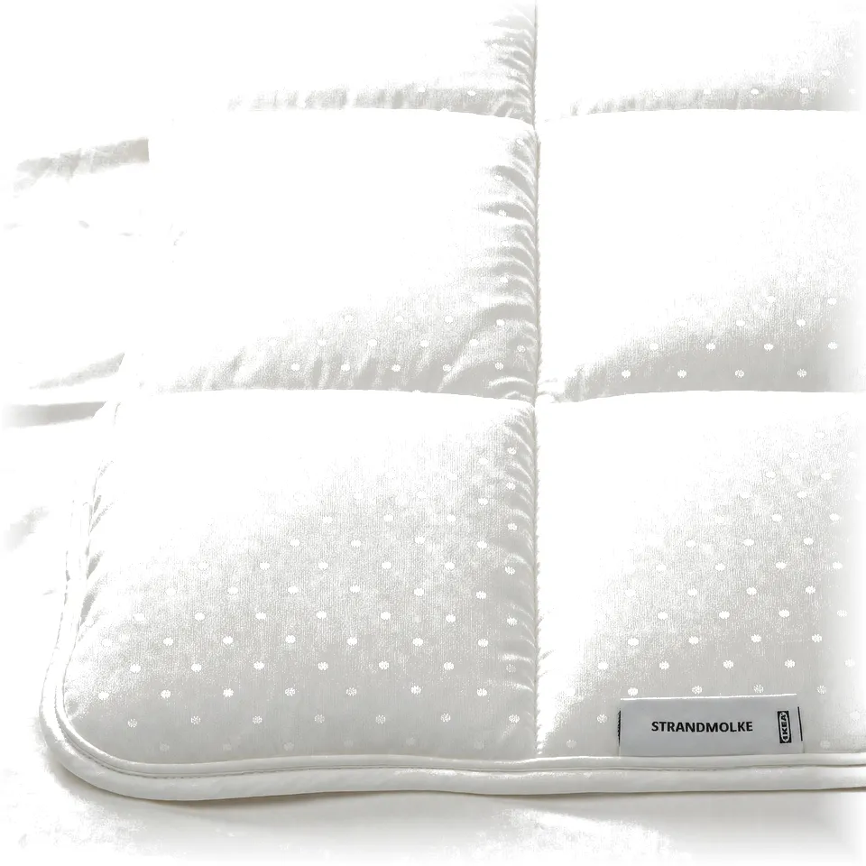 A luxurious, white STRANDMOLKE duvet with a textured, dot-patterned surface. The edges are neatly bound, exuding high-quality craftsmanship.