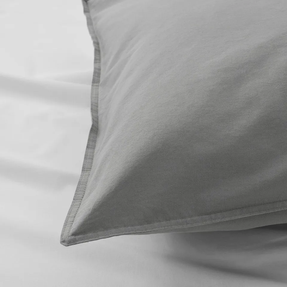 Close-up of soft, grey cotton pillowcase showcasing its smooth texture and neat stitching.