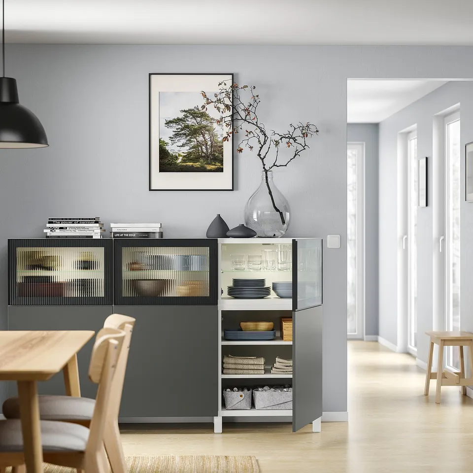 Modern dining room with BESTÅ unit, wooden table, chairs, glass doors, and decor.