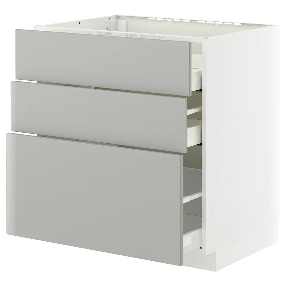 A white IKEA METOD kitchen cabinet with three grey drawers.