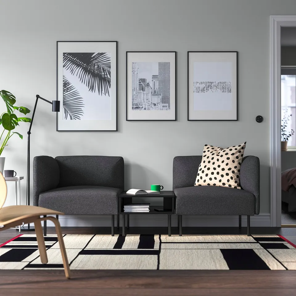 Modern living room with grey LILLEHEM sofas, black coffee table, wall prints, and leopard pillow.