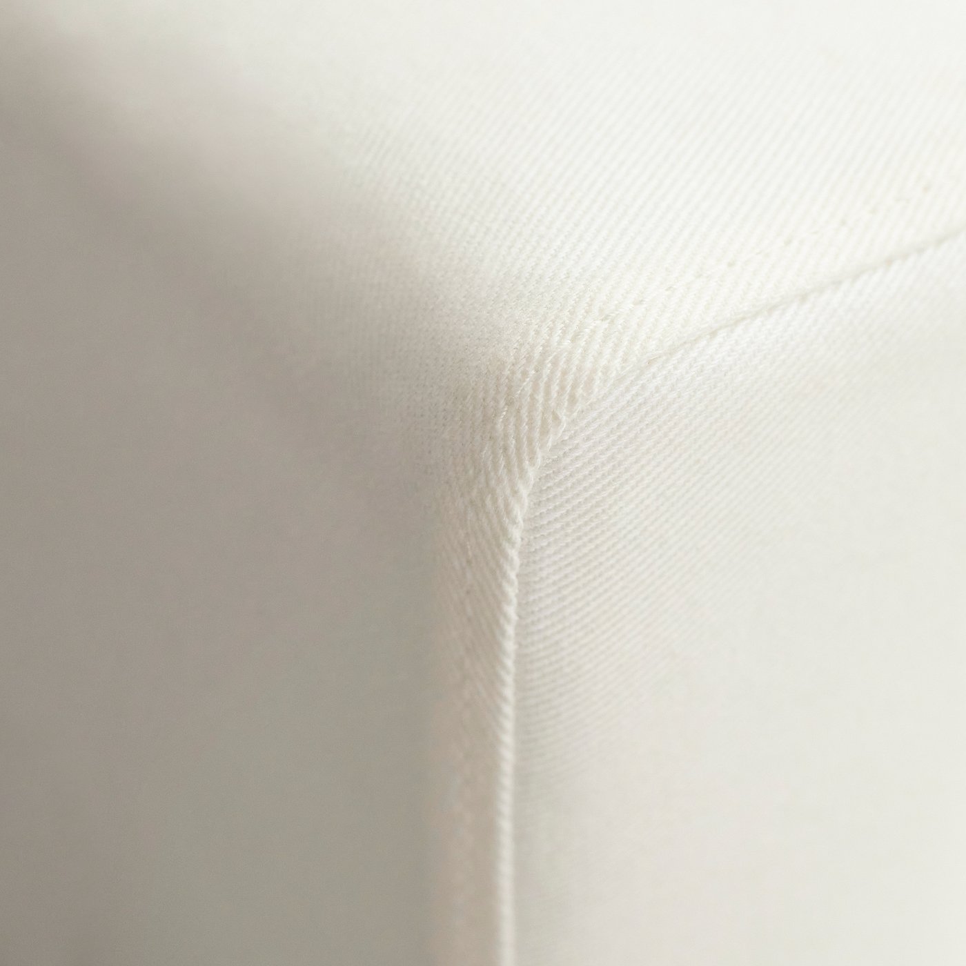 White sofas corner with detailed stitching, smooth fabric, and comfortable cushions.