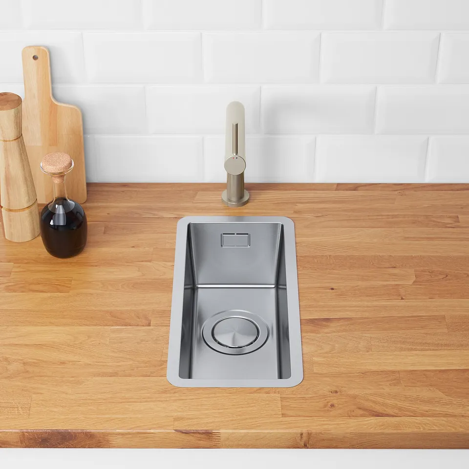 Stainless steel sink on wooden counter with lid magnetically attached, useful for stopping food waste.