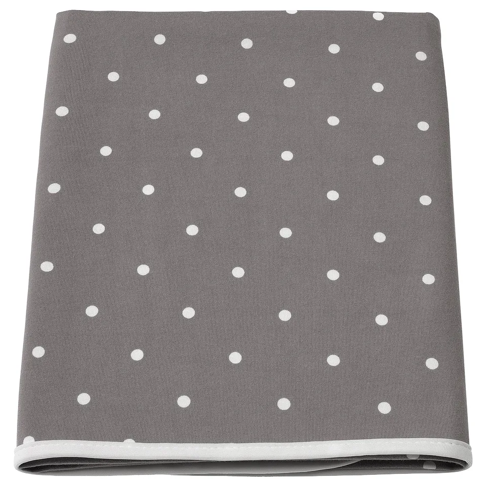 A grey and white polka-dotted babycare mat with a polyester edging and cotton fabric.