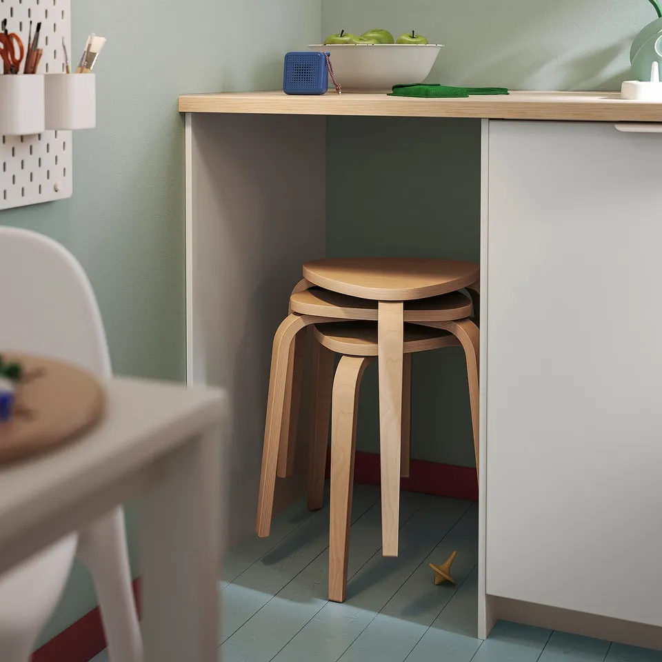 KYRRE light wood stool stacked under green countertop.
