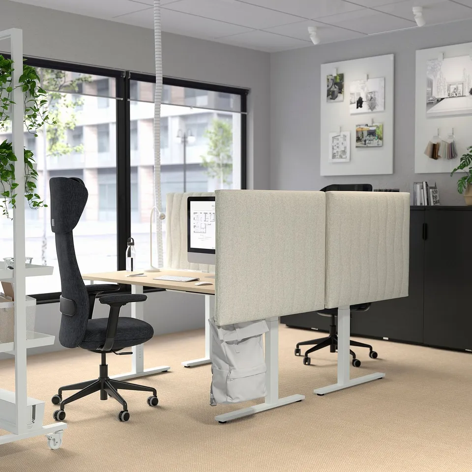 Modern office with MITTZON sit-stand desks in grey-beige, grey chairs, and white decor. Desks are larger, with adjustable height and dual motors.