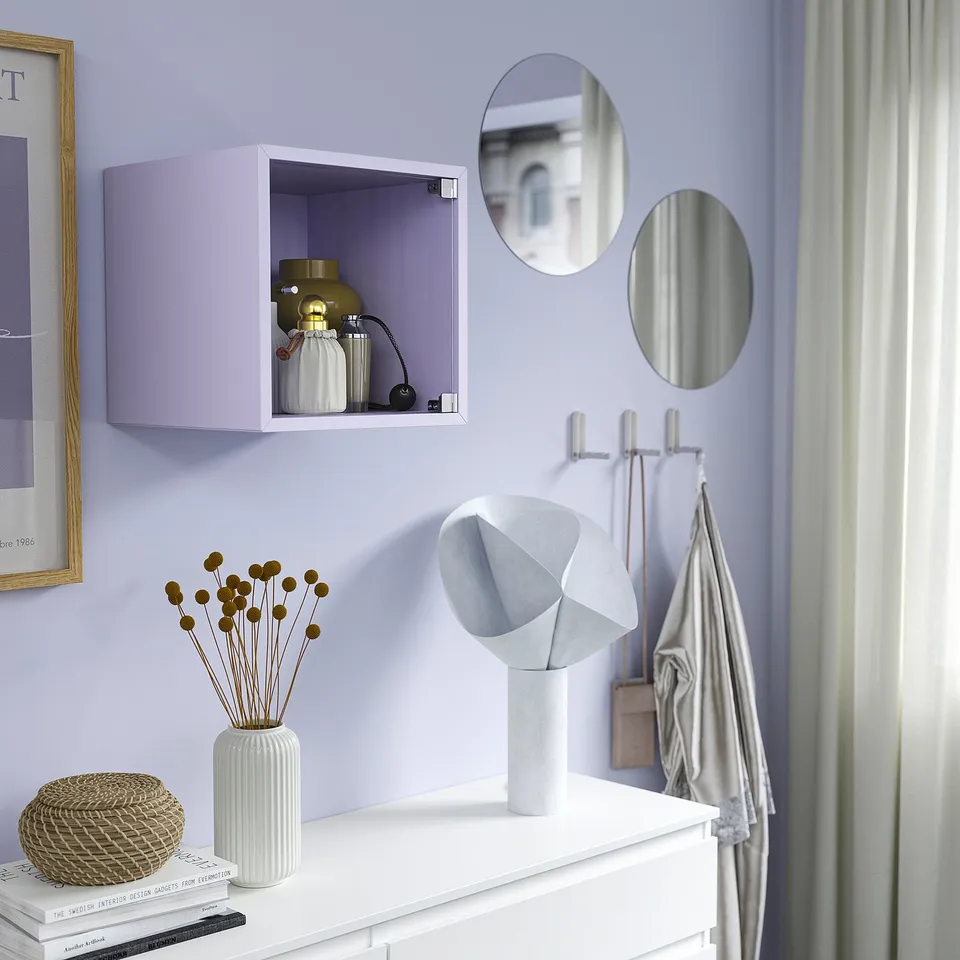 Purple wall-mounted EKET cube shelf stores decorative items, surrounded by round mirrors and adorned with a white lamp.
