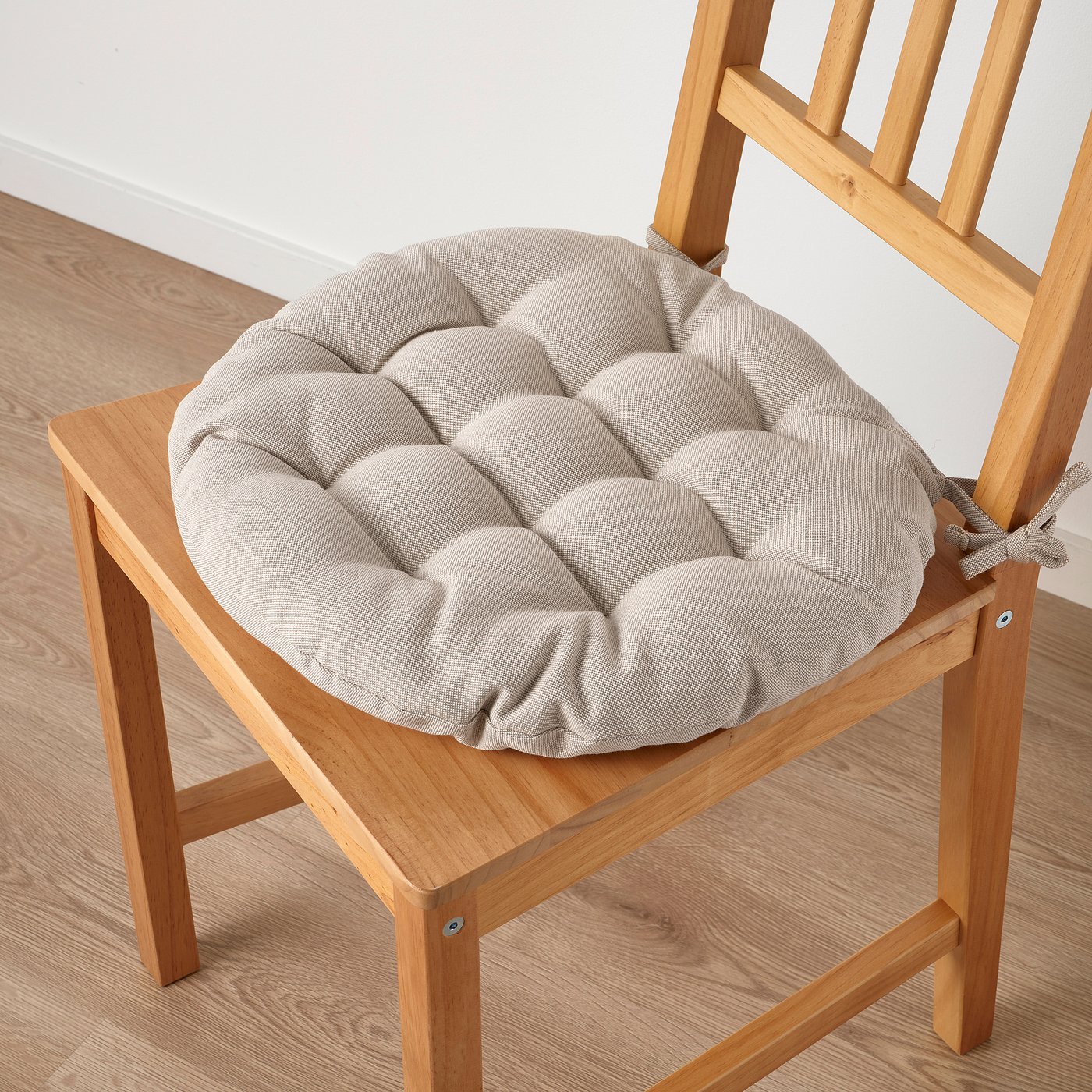 Chair with thick, round cushion. Beige colour, tied for secure fit.