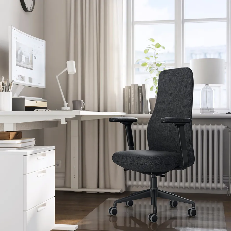 Modern home office: black GRÖNFJÄLL chair with white desk, large window, lamp, and filing cabinet. Ergonomic, adjustable design.