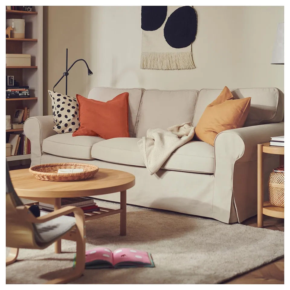 Living room scene with white sofa, colourful pillows, wooden table, and a soft beige rug.