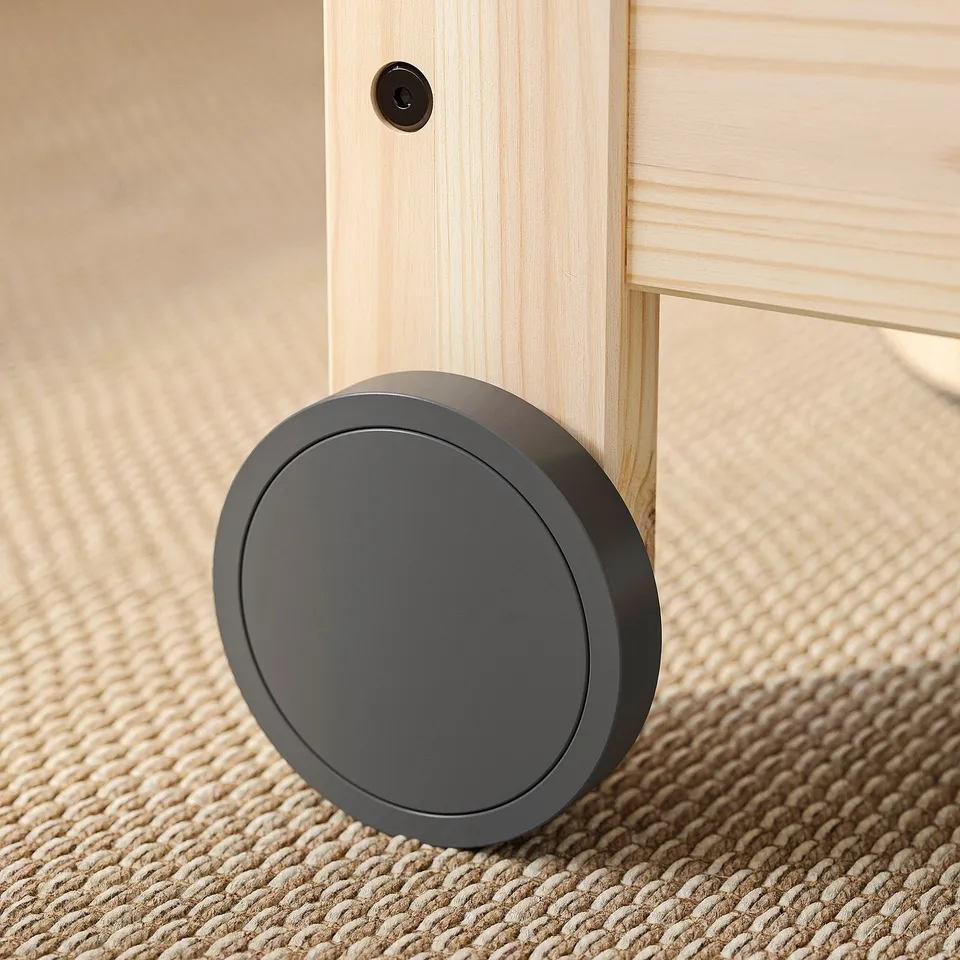 Black castor wheel attached to wooden furniture underframe, showcasing sturdy design and smooth mobility.