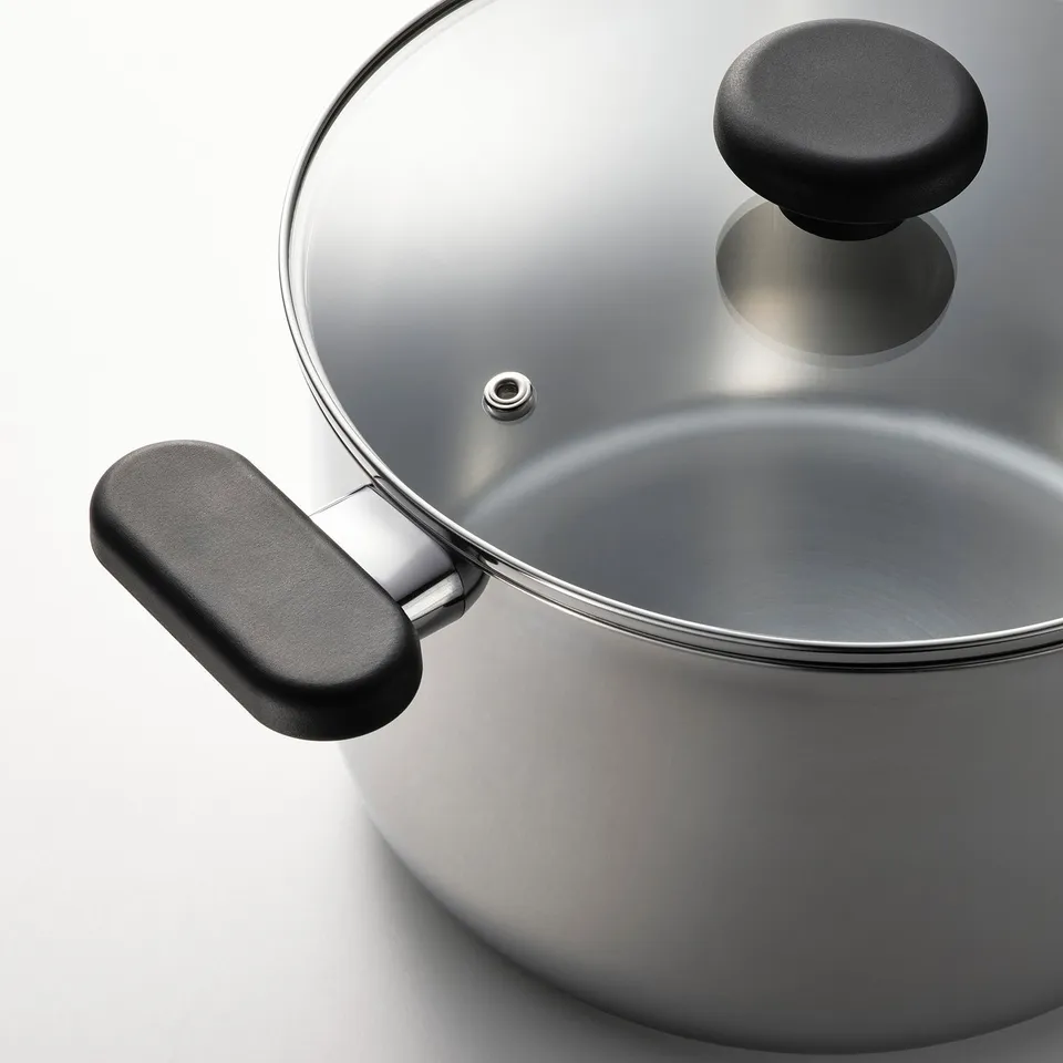 Silver pressure cooker with black handles and glass lid.
