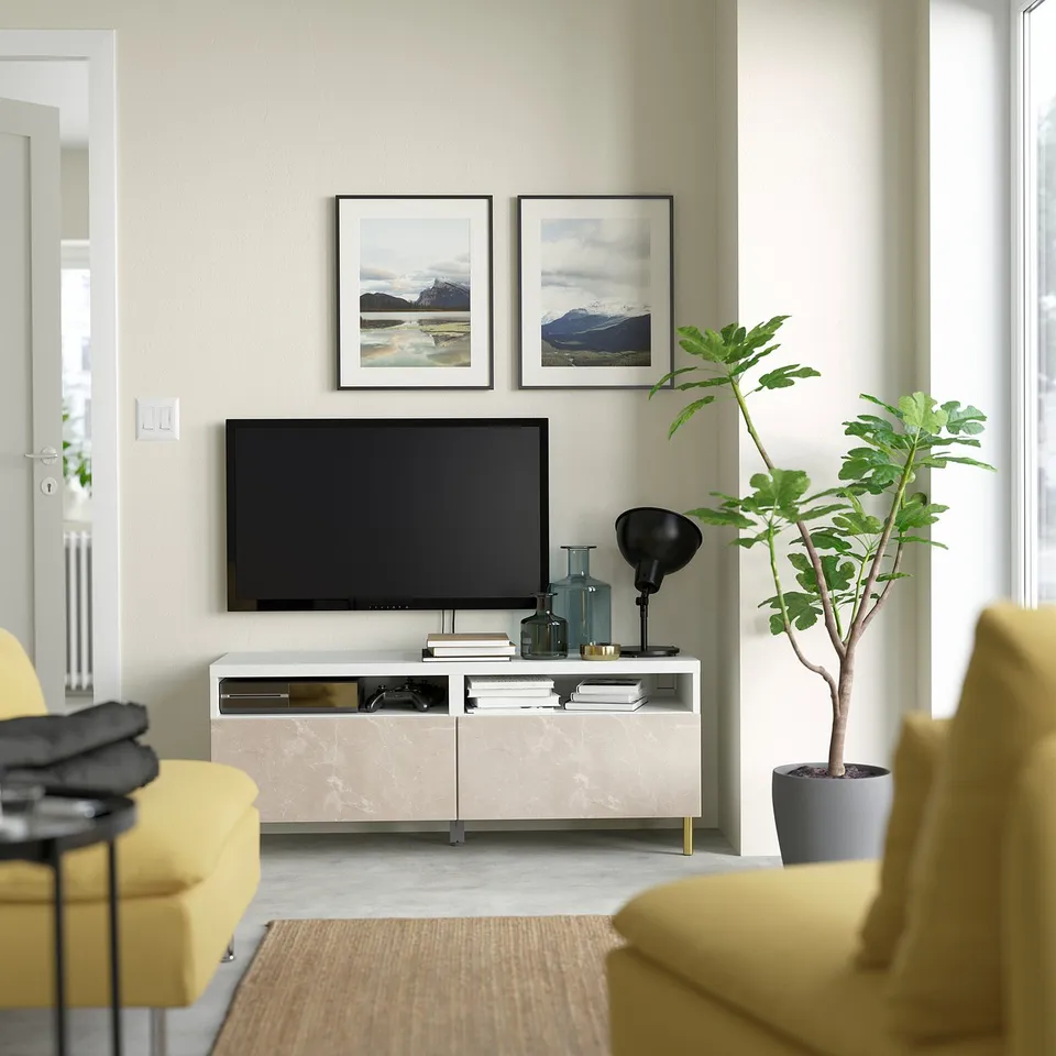 Modern living room with BESTÅ tv stand, minimalist design, flat screen tv, yellow couch, coffee table, trendy pictures, and a large potted plant.